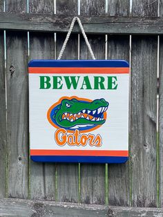 a florida gators sign hanging on a wooden fence with the words beware of alligators