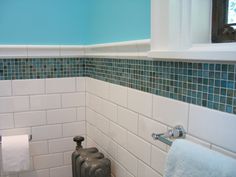 a white toilet sitting under a window next to a towel dispenser in a bathroom