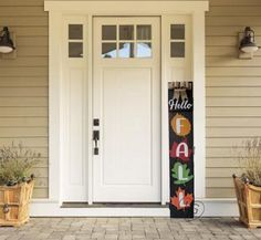 the front door of a house with two planters and a welcome sign on it