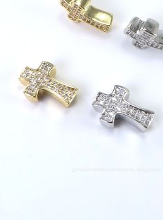 three different types of gold and silver cross pendants on a white surface, one with diamonds in the middle