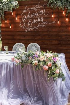 a table with flowers and candles on it in front of a wooden sign that reads, averencel e arenaa