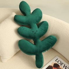 a green stuffed animal laying on top of a white couch next to a magazine cover