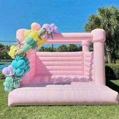 an inflatable bed with balloons and flowers on the top is sitting in grass