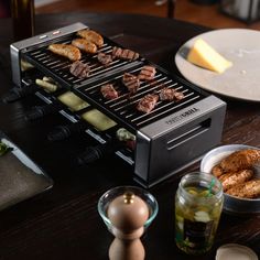 a grill with meats and vegetables cooking on it next to other food items in bowls