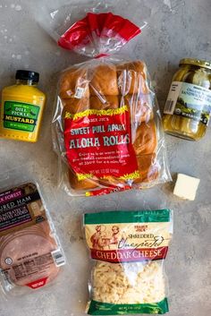 some food is laying out on the counter top, including bread, cheese, and other items