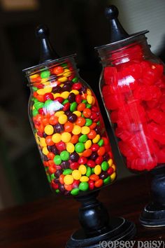 two glass jars filled with candy sitting on top of a table