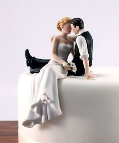 a bride and groom figurine sitting on top of a cake