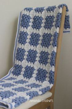 a blue and white crocheted blanket sitting on top of a wooden chair