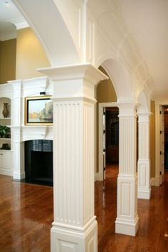 an empty living room with wood floors and white columns