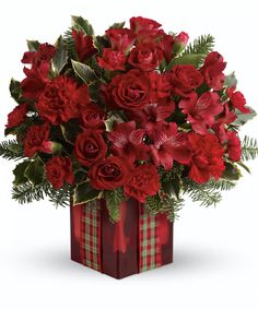 a christmas bouquet with red flowers and greenery in a gift box on a white background