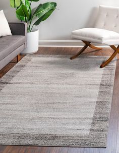 a living room area with a couch, chair and large rug on the hardwood floor