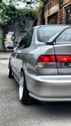 the back end of a silver car parked in front of a building