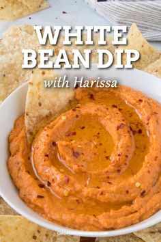 white bean dip in a bowl with tortilla chips around it and the title overlay reads, white bean dip with harissa