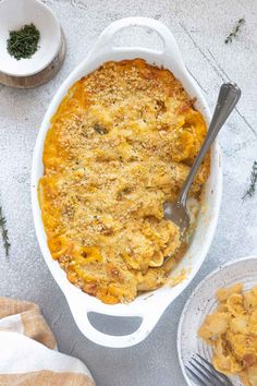 a casserole dish filled with macaroni and cheese next to two plates