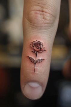 a small rose tattoo on the middle finger