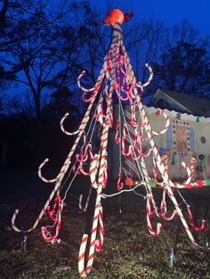 a christmas tree made out of candy canes in front of a house at night