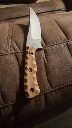 a large knife is stuck in the back of a couch with button holes on it