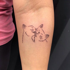 a woman's arm with a small tattoo of two cats on the left side