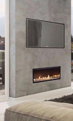 a living room with a couch and a tv mounted on the wall next to a fire place