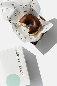 a half eaten donut sitting on top of a white paper wrapper next to a box