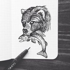 a drawing of a bear holding a fish on top of a notebook with a pen next to it