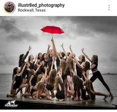 a group of young women standing next to each other on top of a pier under an umbrella