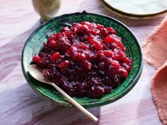 a green bowl filled with cranberry sauce on top of a table