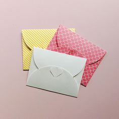 three envelopes with different colored paper on top of each other and one has a heart in the middle