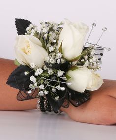 a bridal bouquet with white roses and baby's breath is on the arm of a woman