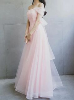 a woman wearing a pink dress standing in front of a wall