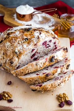 a loaf of bread sitting on top of a wooden cutting board next to nuts and butter