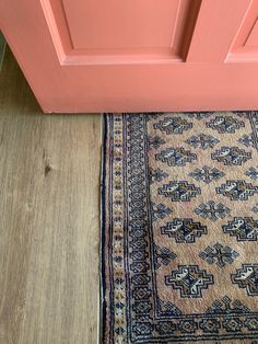 an old rug on the floor in front of a door with pink painted paneling