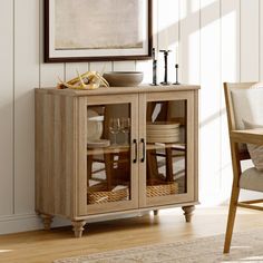 a wooden cabinet with glass doors in a room next to a chair and table on the floor