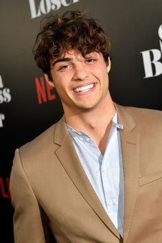 a smiling young man in a tan suit