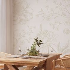 a wooden table topped with a vase filled with flowers next to two wicker chairs