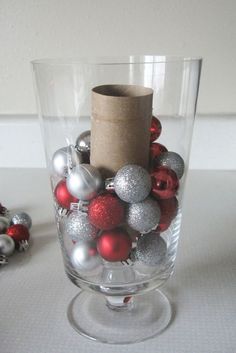 a glass vase filled with ornaments and a roll of paper sticking out of the top