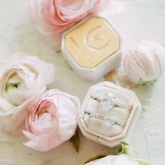 wedding rings and flowers on a white table with pink roses in the foreground, closeup