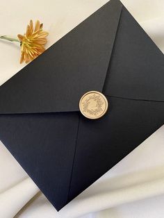 a black envelope with a wax stamp on it and a flower in the corner next to it