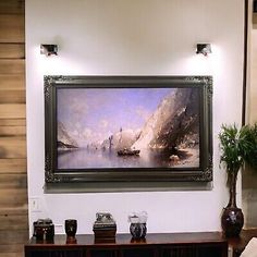 a large painting hanging on the wall above a wooden table with vases and other items