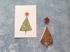 a card with a christmas tree on it next to a rubber stamp and a star