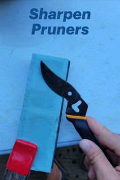 a person holding a knife in front of a sharpen pruners box with the handle cut off