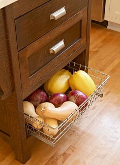 an open drawer in a kitchen filled with fruits and veggies on a wooden floor