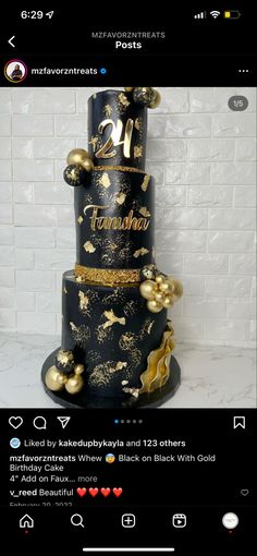 a black and gold birthday cake with golden decorations on it's tiers, sitting in front of a white brick wall