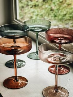 four wine glasses sitting on top of a window sill