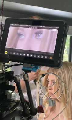 a woman with long blonde hair is looking at an image on the screen while holding a camera