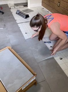 a woman in an orange shirt is working on a floor