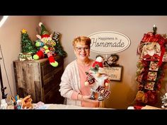 a woman holding a stuffed animal in front of a christmas tree and other holiday decorations