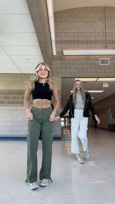 two women standing next to each other in an empty building with their hands on their hipss