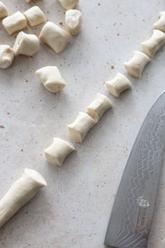 a knife is on the counter next to some dumplings and pieces of food that have been cut up