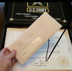 a person is holding an envelope in front of the u s army seal and document